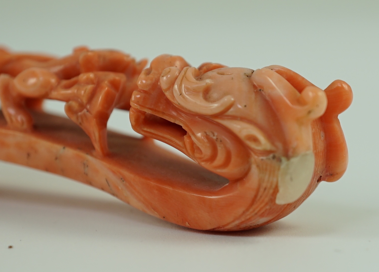 A rare Chinese coral 'dragon' belt hook 18th/19th century, 9.2 cm long, small loss to dragon horn, wood stand